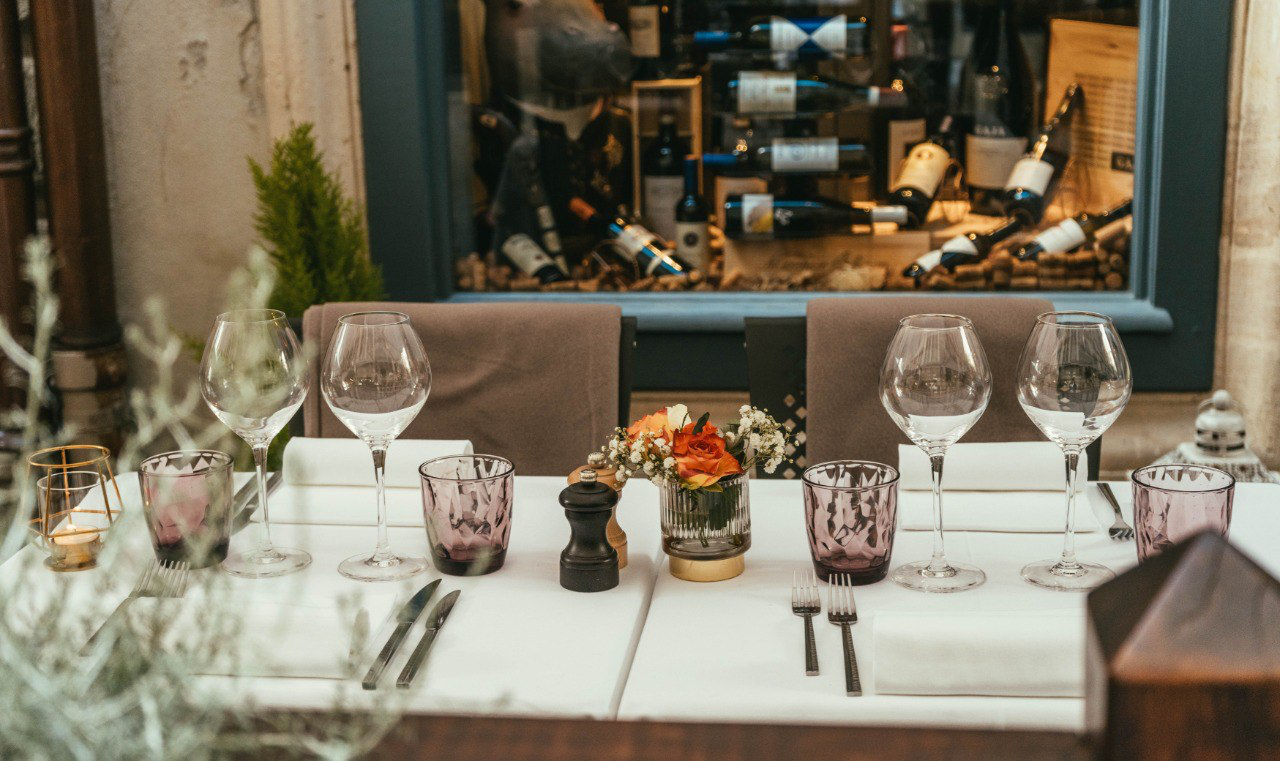 Table gastronomique du restaurant La Finestra avec verres à vin et cave à vins en arrière-plan